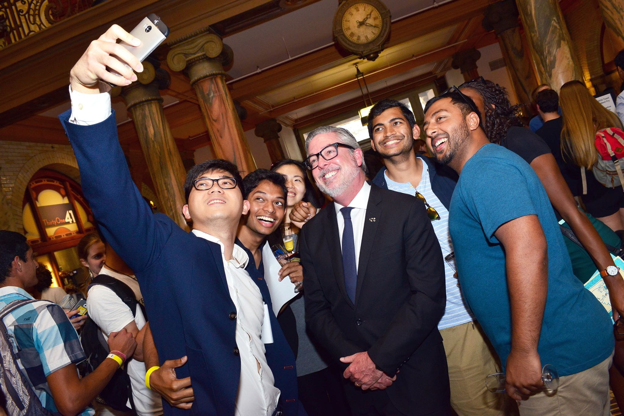 President John Fry taking a group selfie with graduating seniors at the Senior Toast event which was held in the lobby of Main Building.