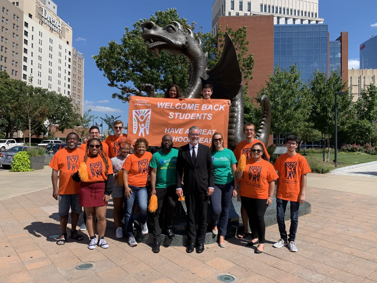 President John Fry posing in front of Mario the Dragon statue next to members of the West Philly Promise Neighborhood school team.