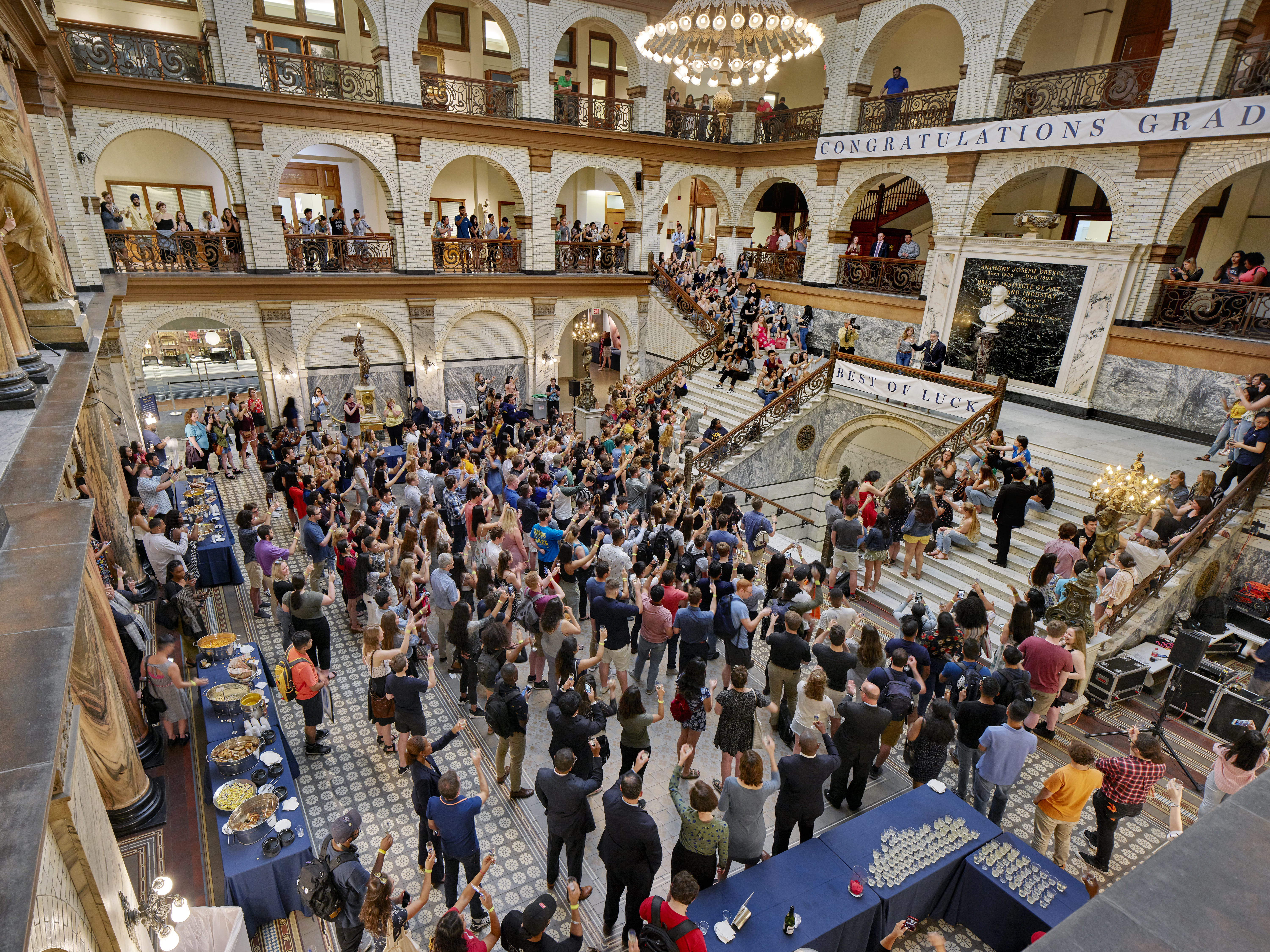 An aerial shot of President John Fry making a speech at the Senior Toast in the lobby of Main Building. All of the graduating seniors in the audience are holding up their glasses.