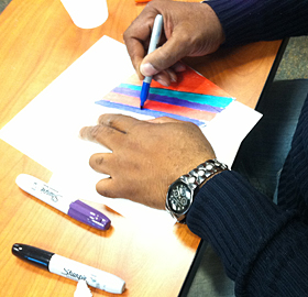 A participant in the Porch Light Initiative draws with colorful markers.