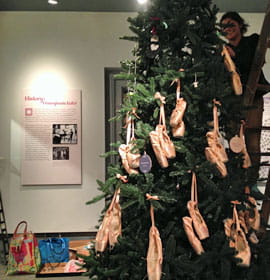 A 10-foot Christmas tree decorated with pointe shoes is installed at the entrance to the exhibit