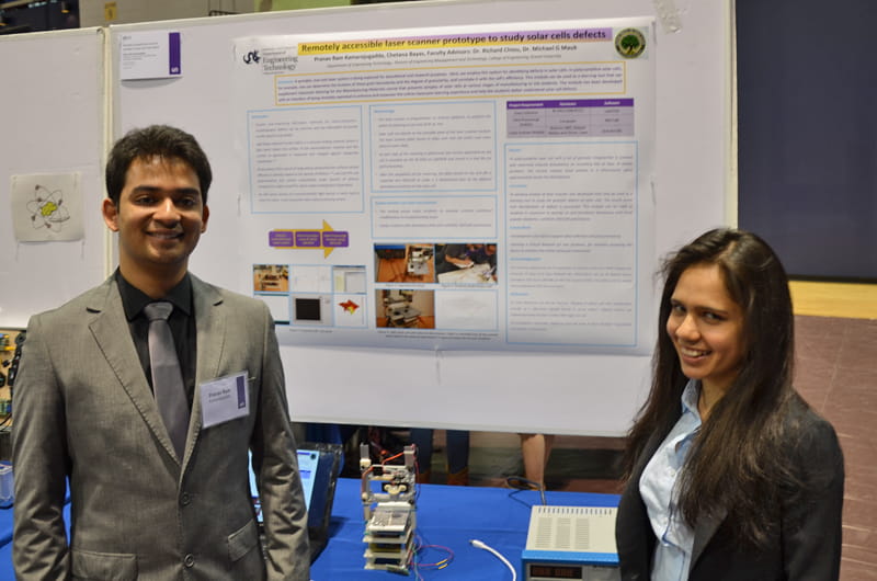 Pranav Ram Kamarajugadda (left) and Chetana Bayas (right) stand with their prototype laser scanner for detecting defects in solar cells.