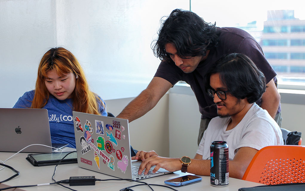 Photo of three people looking at laptop screens during Philly Codefest