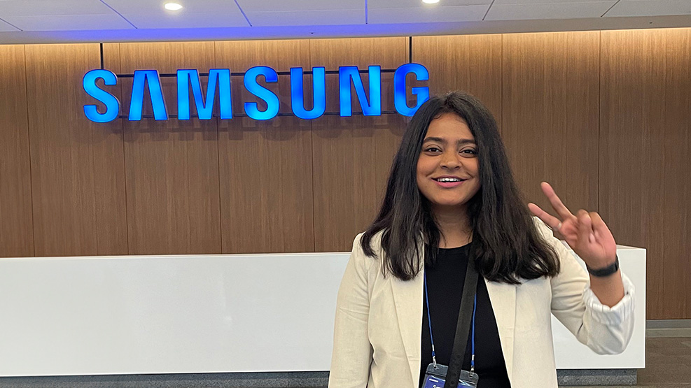 Ankita Paul stands in front of a Samsung sign.
