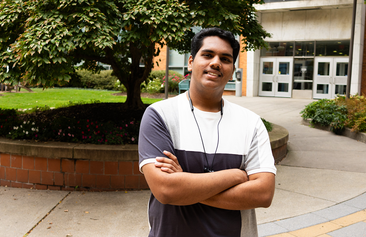 A student standing in a courtyard in front of a tree.