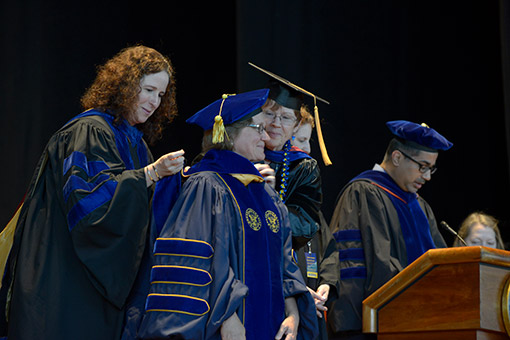 Graduate students receive their hoods.