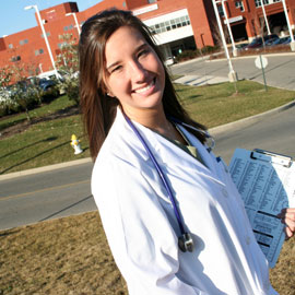 woman in lab coat standing before a hospital