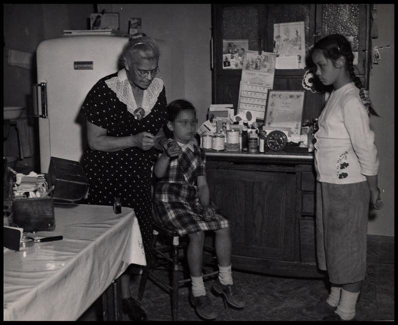 Dr. Lillie Rosa Minoka Hill applying first aid for Carol Hause, while her sister Loretta watches intently.
