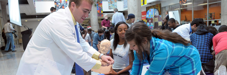 A Drexel medical student/resident at an AHA CPR event demonstrating CPR to kids.