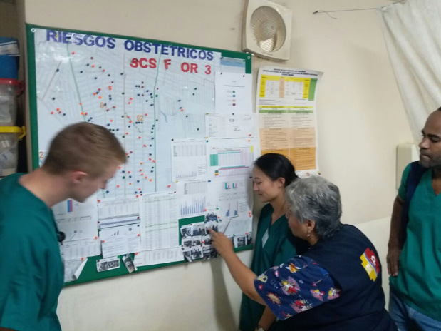 Drexel med student Garrett Mayo in the health clinic of Guayaquil; a board to monitor pregnant patients, including risk level.