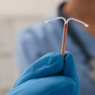 Doctor holding T-shaped intrauterine birth control device.