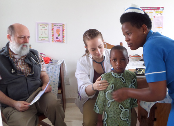 Clare Coda examines a young patient in Uganda as her father looks on.