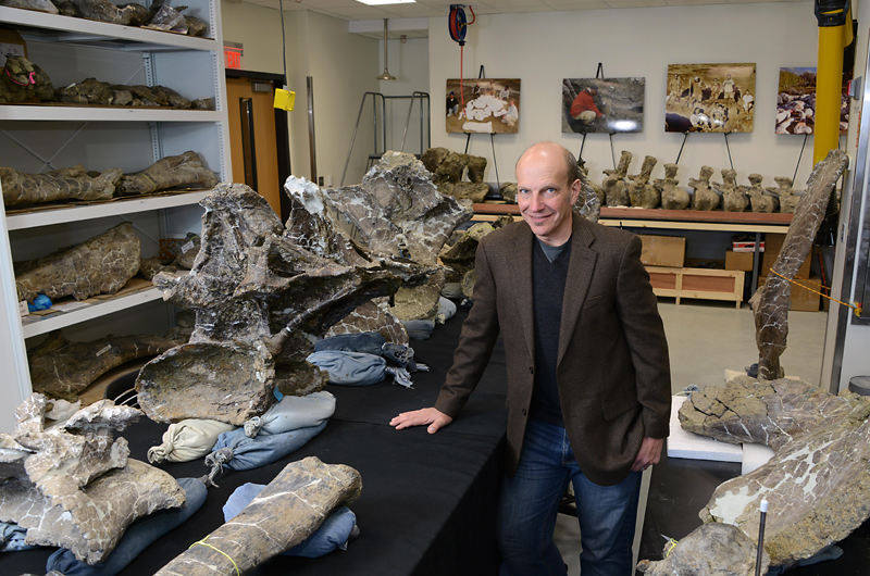 Kenneth Lacovara, PhD, stands in his lab among the bones of the exceptionally complete dinosaur skeleton he discovered in Patagonia.