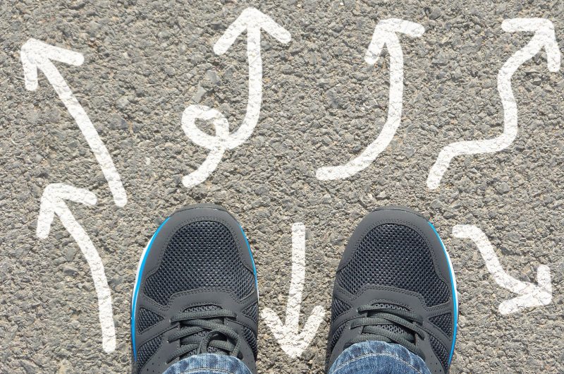 An image of feet with arrows symbolizing directions of a life course