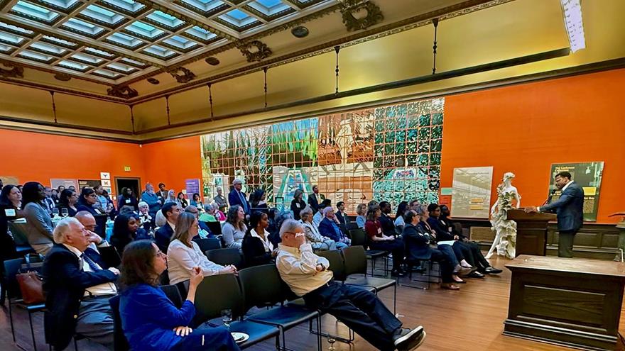 A room full of people in the A.J. Drexel Picture Gallery watches a student speaker at a podium.