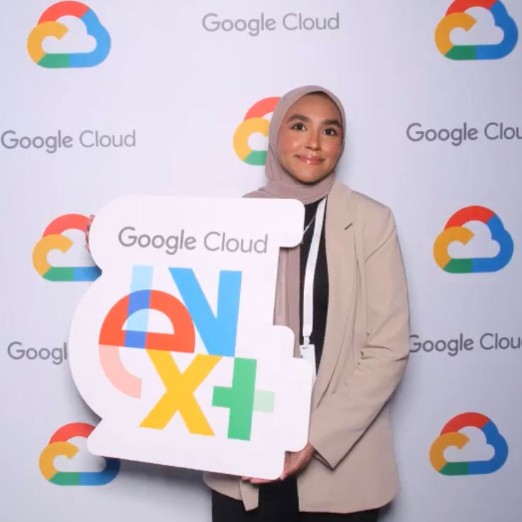 Photo of Muneera Cadersa standing in front of Google Cloud Conference banner