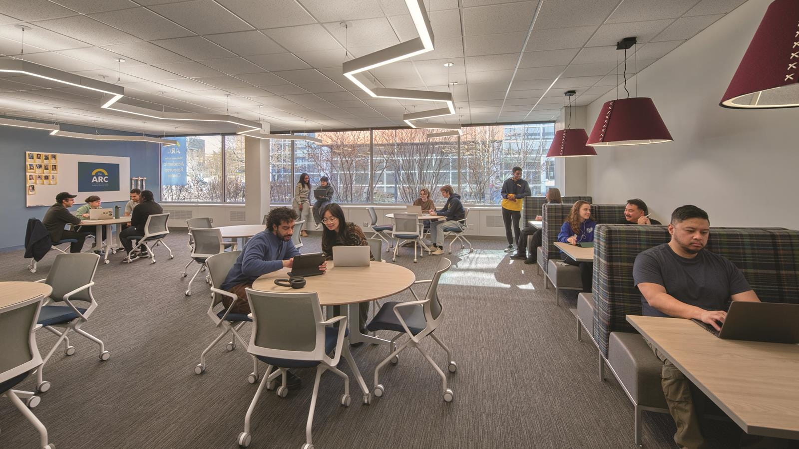 Students in a lounge area of the Academic Resource Center. Most are studying either by themselves or in a group in front of their laptops.