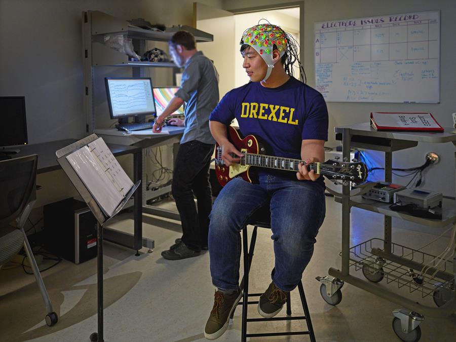 Male student plays guitar while participating in brain mapping research