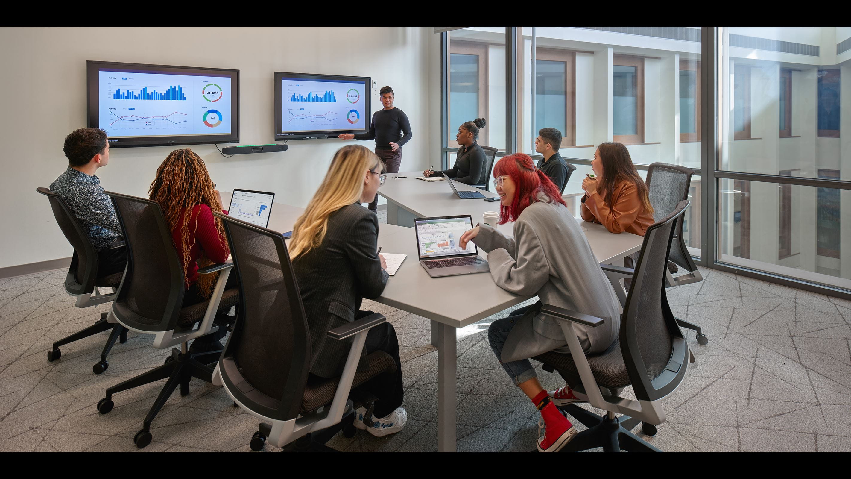 A student giving a financial presentation to a group of fellow students in a conference room