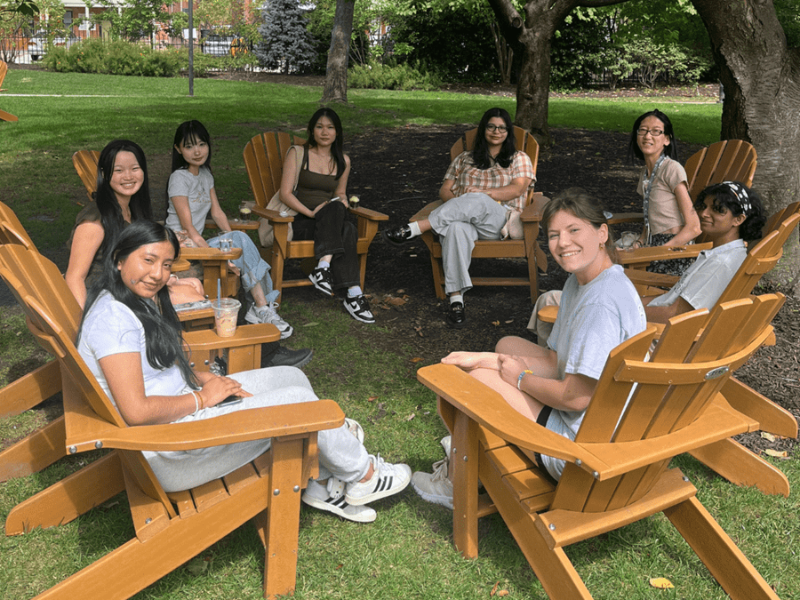 Group of students sitting in Adirondack chairs on grass