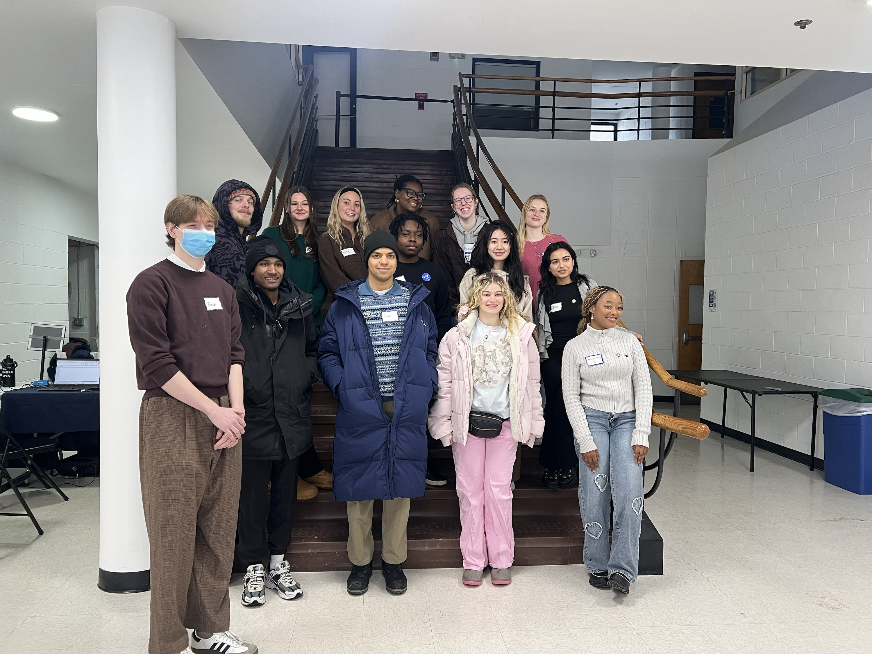 a group of people stand together in front of a flight of stairs. 