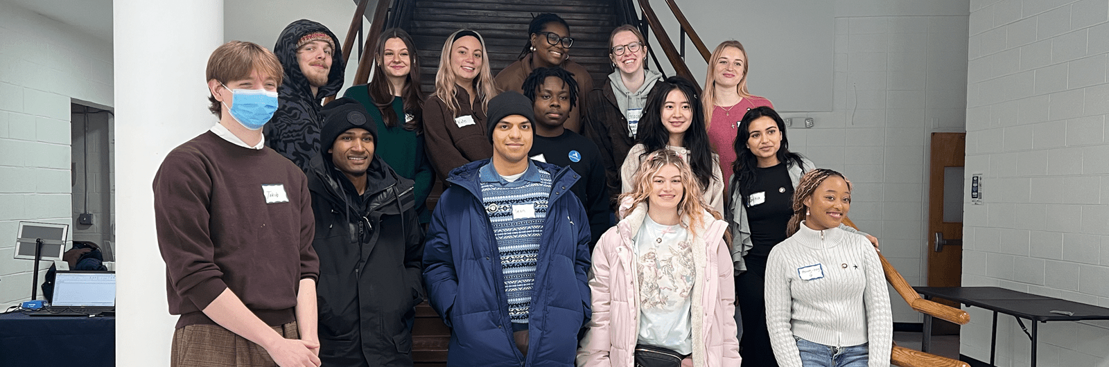 a group of people stand together in front of a flight of stairs. 