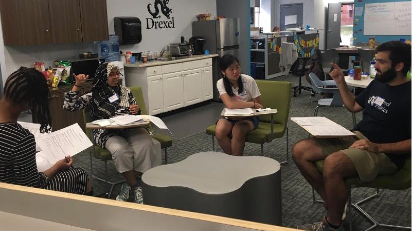 Four student leaders sitting at desks in the Lindy Center for Civic Engagement having a discussion 