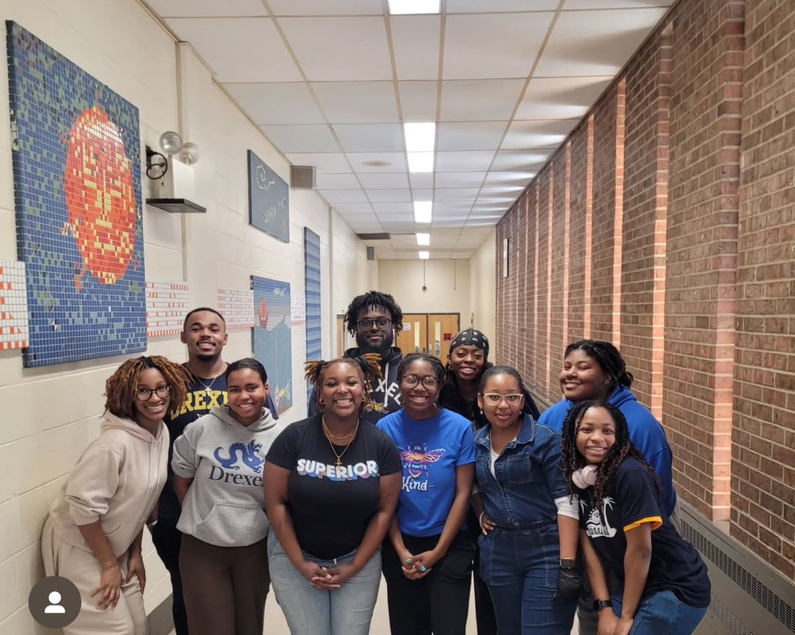 10 students from NAACP/NCNW groups pose smiling in a school highway.