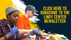 Image of two students making peanut butter and jelly sandwiches - one student has dark skin and a grey beanie and the other has light skin and a gray hat. They are both wearing purple gloves. THe text on the image reads "For up-to-date news, event announcements, and volunteer opportunities