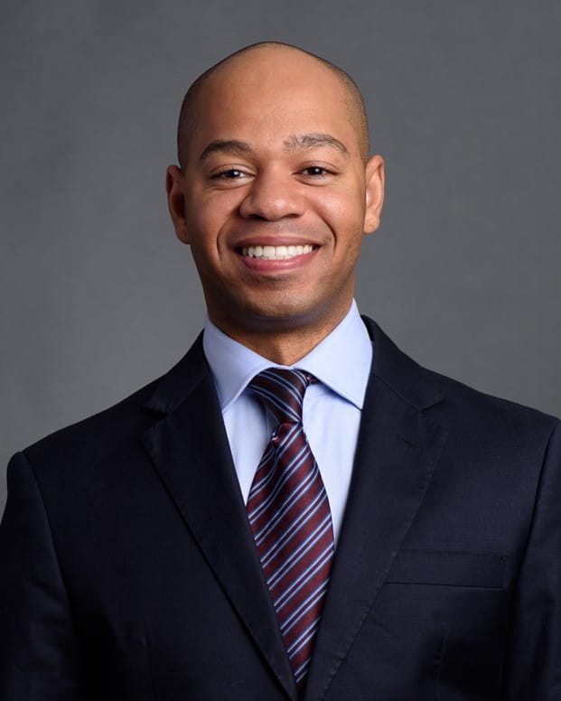 Smiling person wearing a suite and tie with gray background