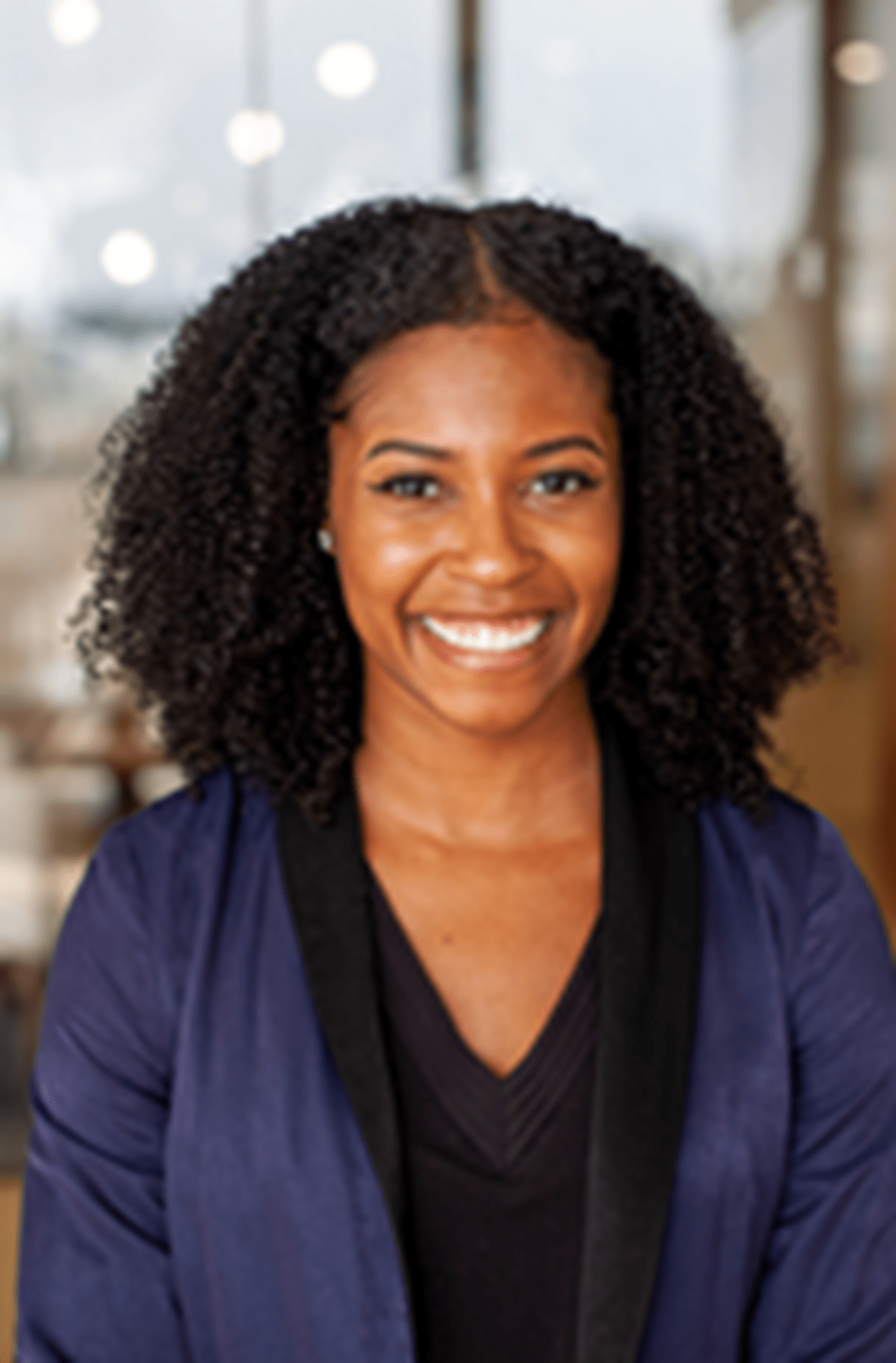 Smiling person with black shirt and blue blazer
