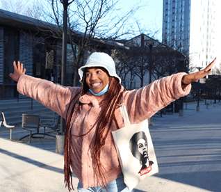 Person smiling with arms outstretched wearing white hat and pink jacket