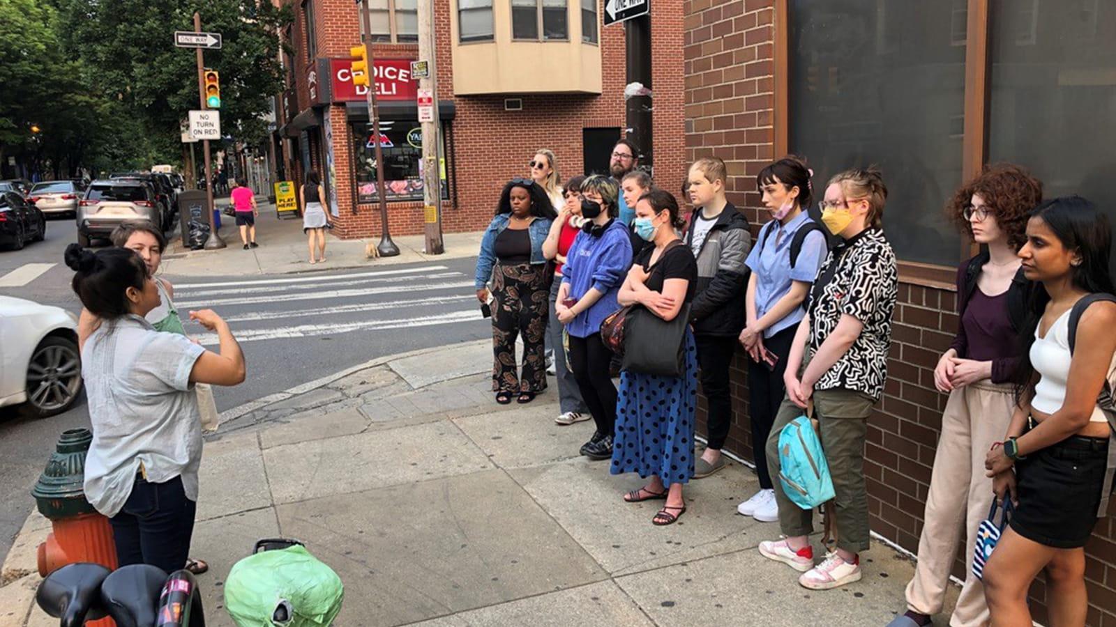 Sanctuary Cities Class Spring 2023 students standing outside listening to a speaker
