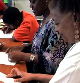 Women and children at the 11th Street Family Health Services draw and write as part of an educational or integrative health program.