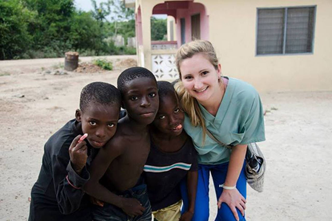 Student in scrubs with children
