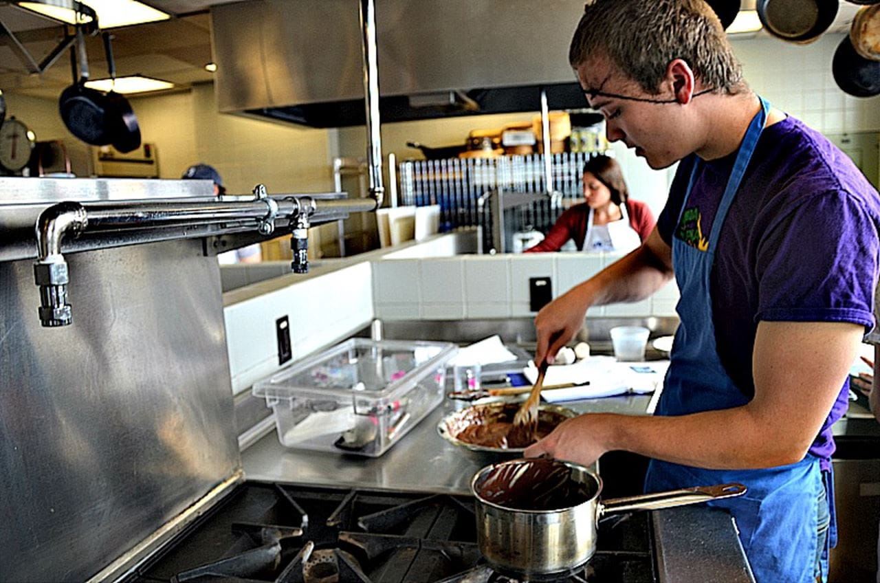 Zachary Gibbons, a freshman chemical engineering major, prepares for a layered chocolate cake with a chocolate glaze in the "Chocolat" class.