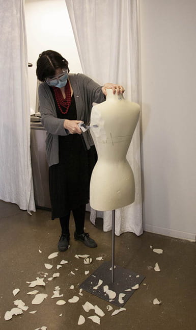 Clare Sauro, curator of the Fox Historic Costume Collection, working on a mannequin to slim it down to display a garment in Immortal Beauty. Photo by Michael J. Shepherd.