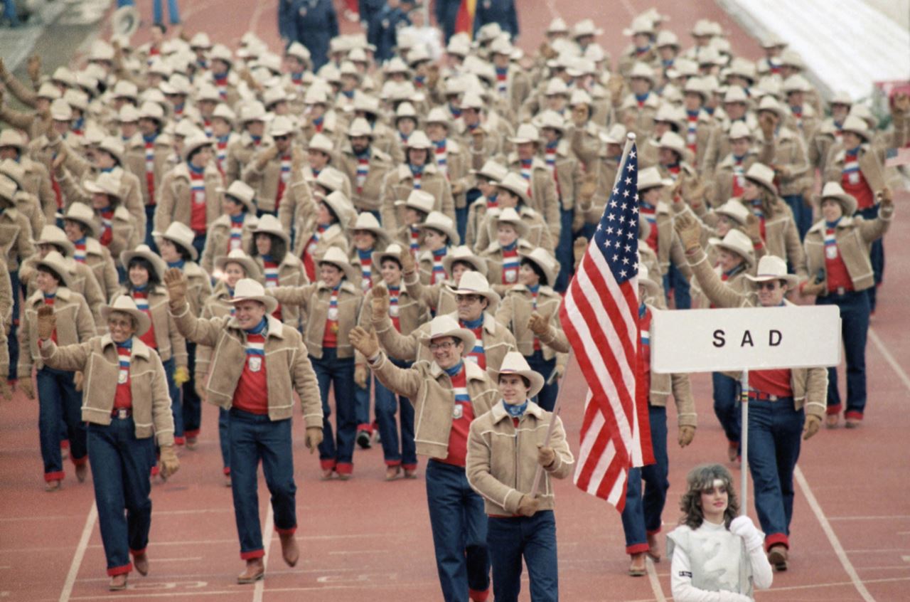 Frank Masley '89 holds the American flag during the 1984 Winter Olympics. Placad marked sad is the Yugoslav designation for USA. (AP Photo/Jack Smith)