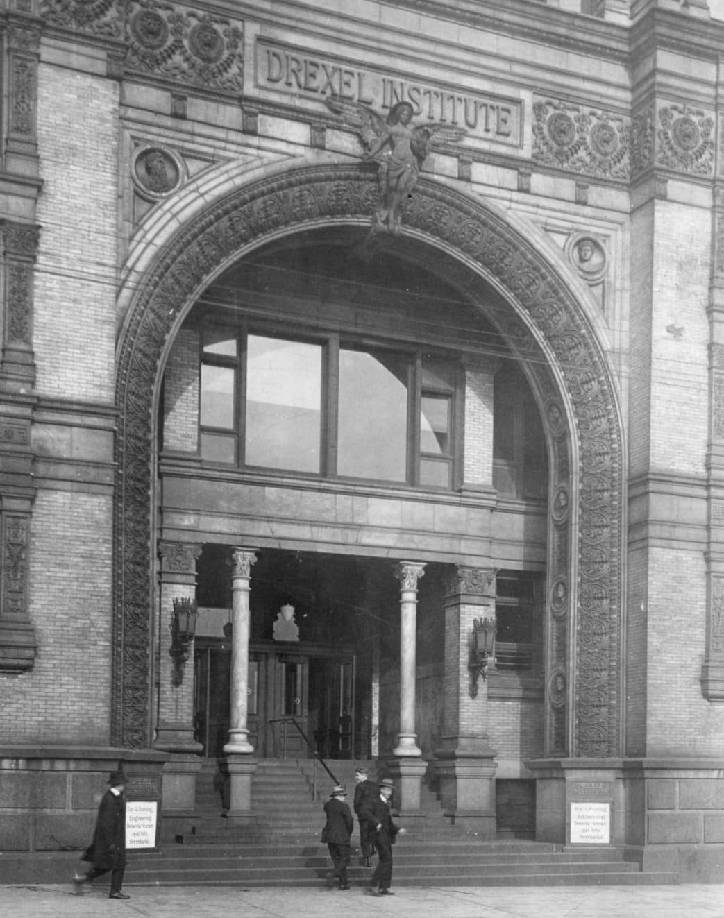 A 1915 photo of Main Building's Chestnut Street entrance. The white blocks on the bottom of the archway advertised some of Drexel's current classes: "day and evening school, engineering, domestic science and arts and secretarial." Photo courtesy University Archives. 