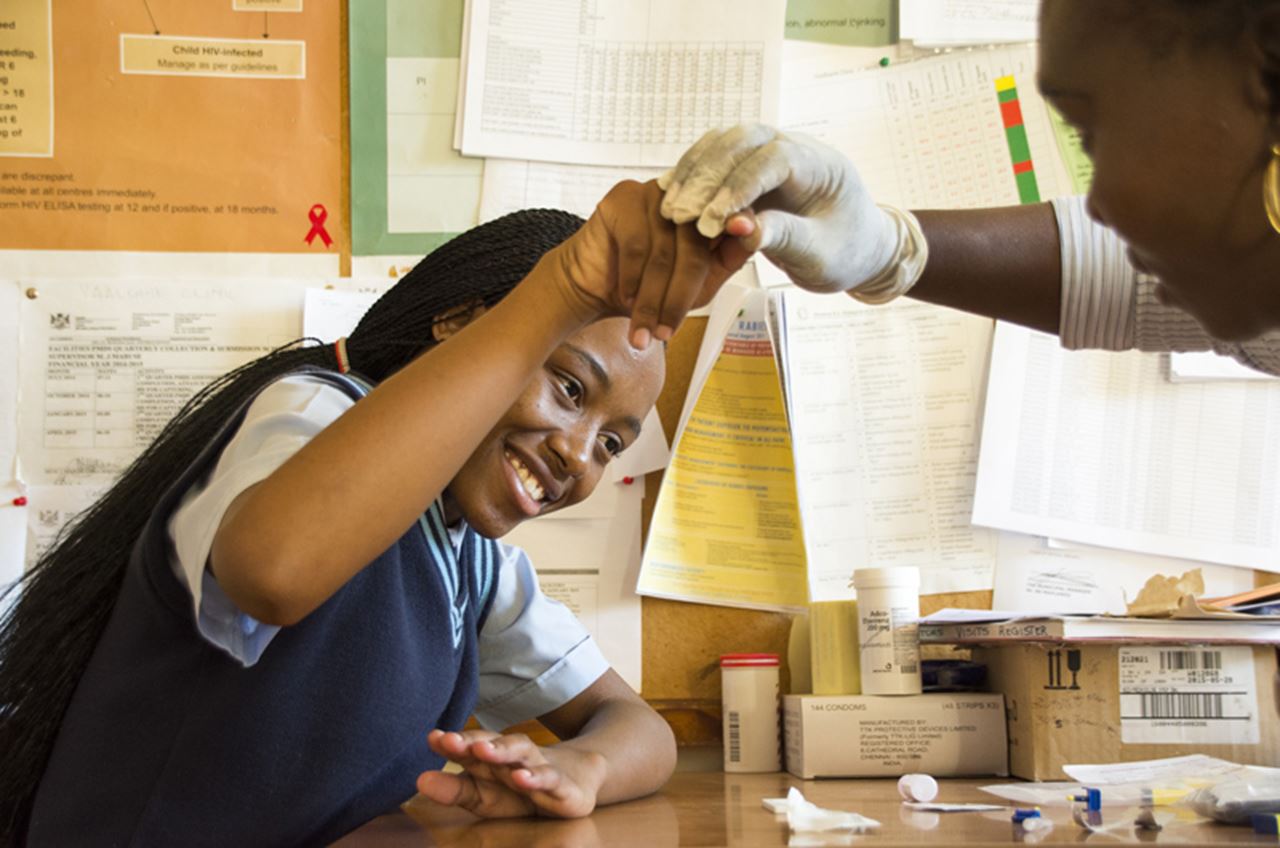 A young girl holding her finger out for an HIV test.