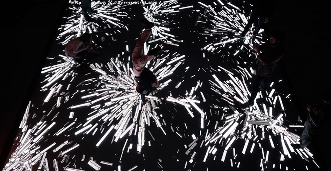 David Kassie (computer science) does a handstand on Symmetry Lab x IBM's interactive LED dance floor.