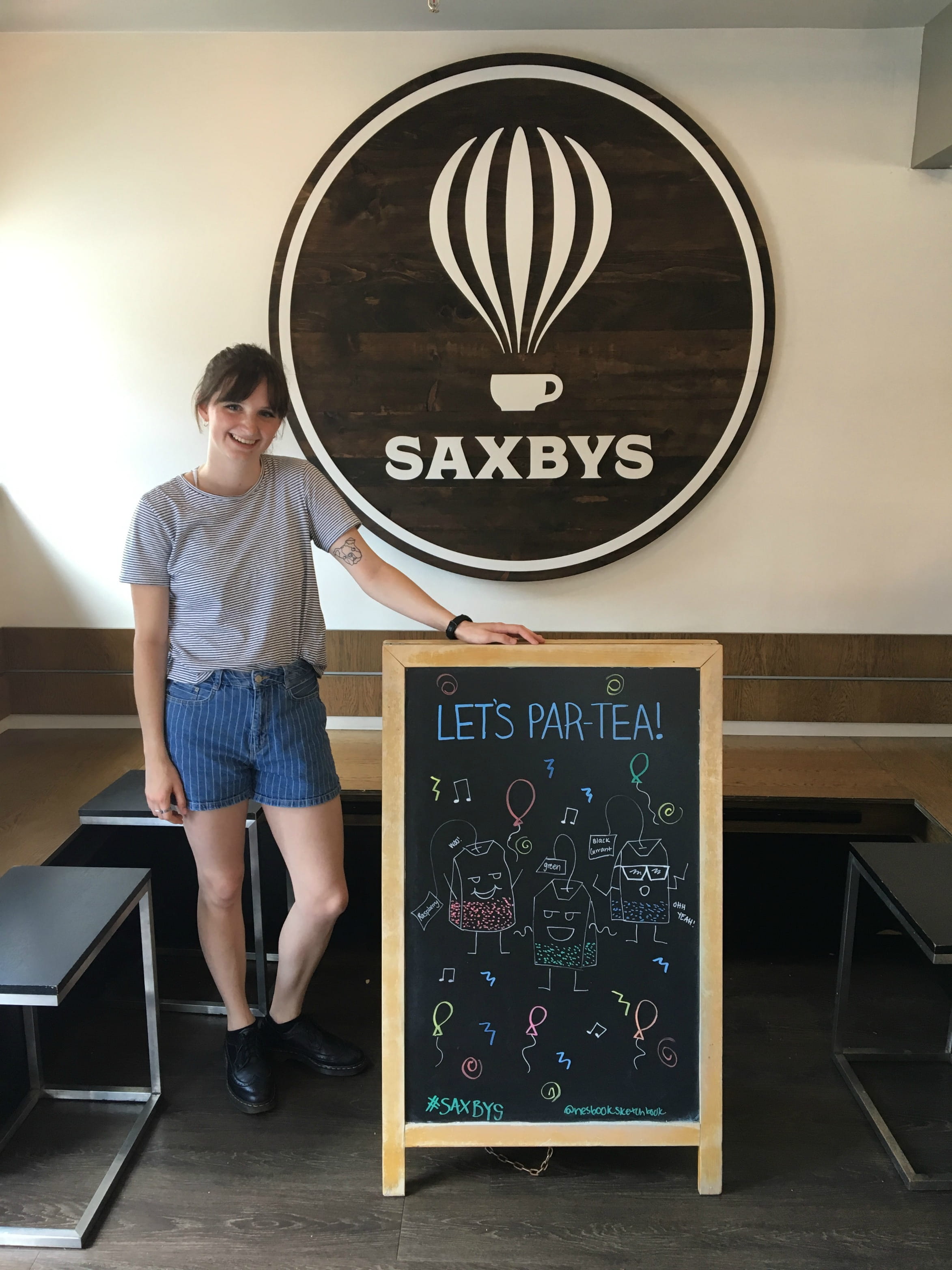 Graphic design major Abbey Nesbitt poses with one of the Saxbys chalkboard signs displaying her art.