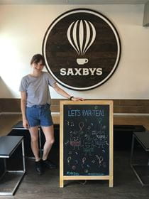 Graphic design major Abbey Nesbitt poses with one of the Saxbys chalkboard signs displaying her art.