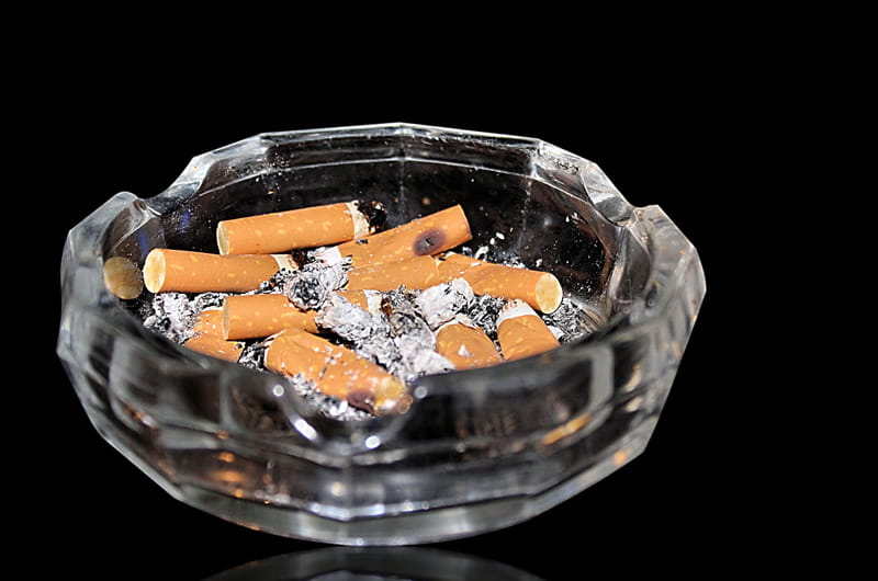 A glass ash tray full of cigarette butts
