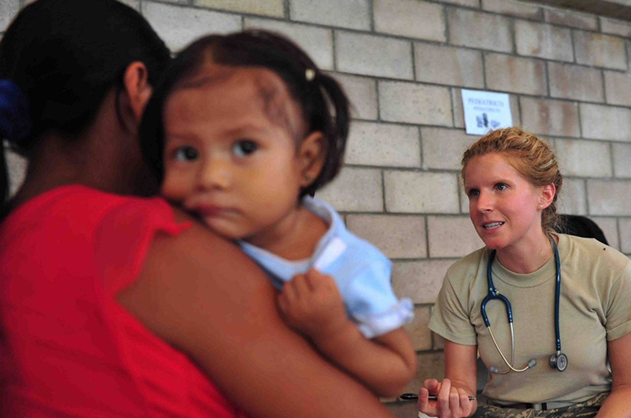 A pediatrician talking to a woman who has her daughter in her arms