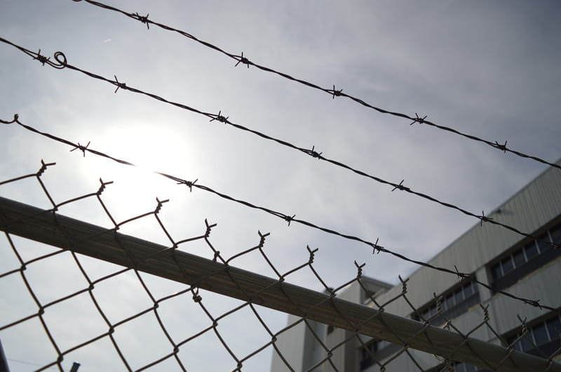 Barbed wire fencing with a prison building in the background