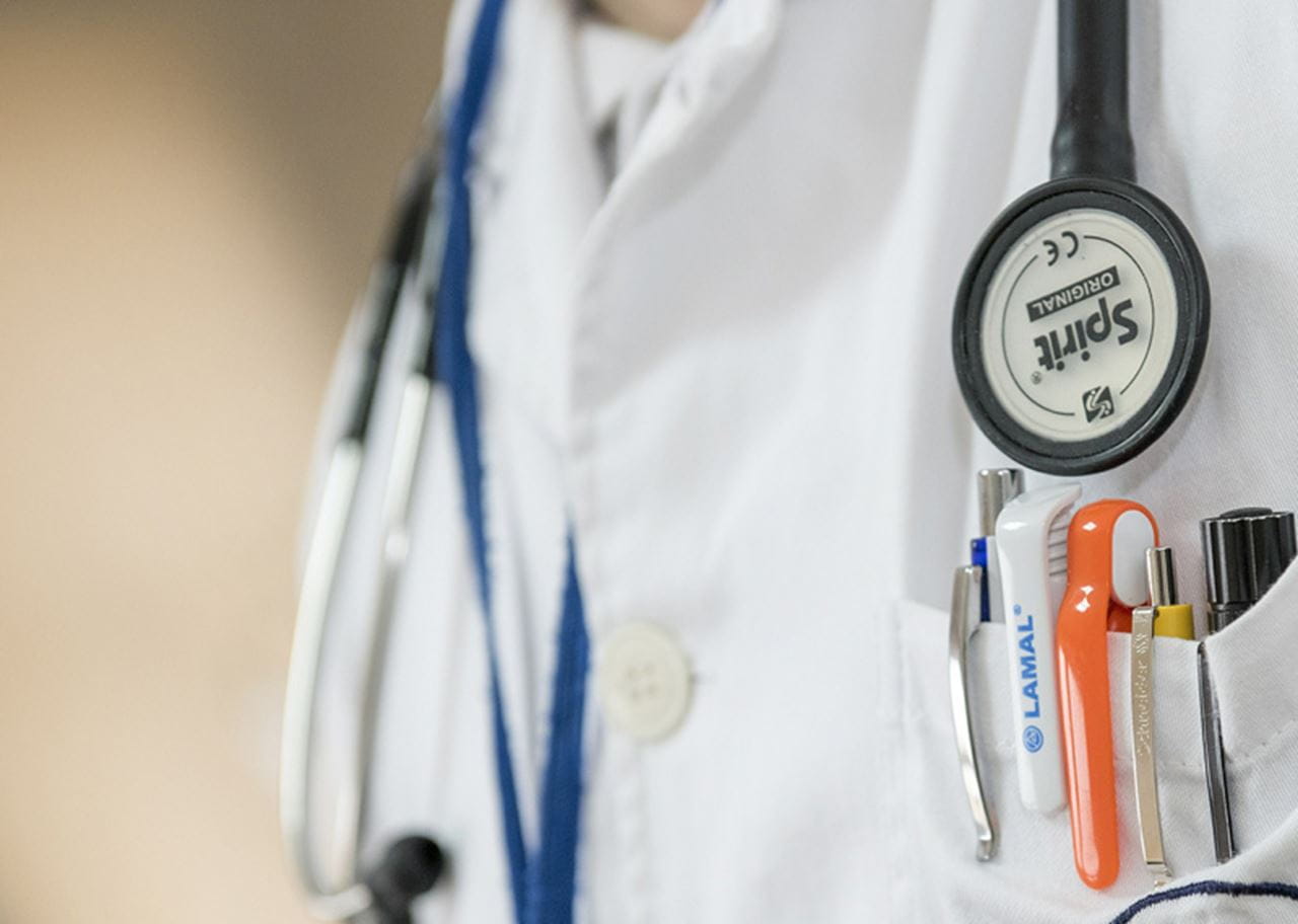 A doctor's white coat with pens that include a drug company's name.