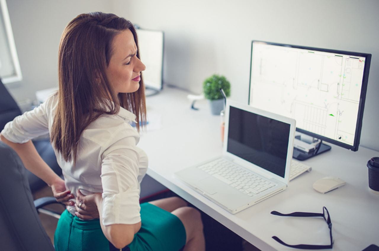 photo of a woman with back pain at an office desk