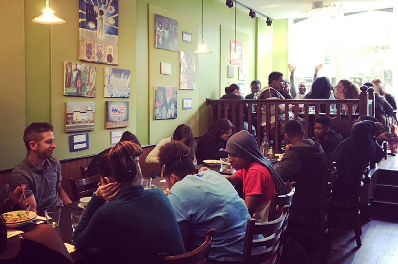 A room full of people eating at tables.