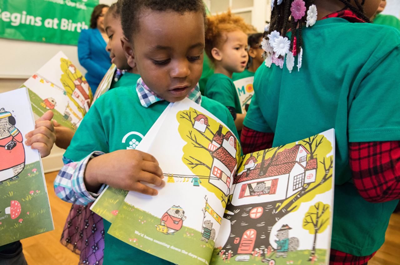 A child holds a book and looks through the pages